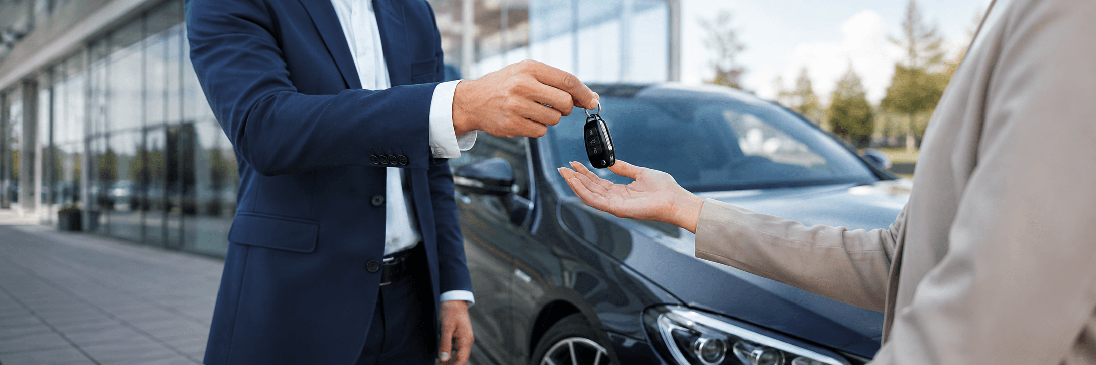 Handing over the keys to a renter beside the vehicle